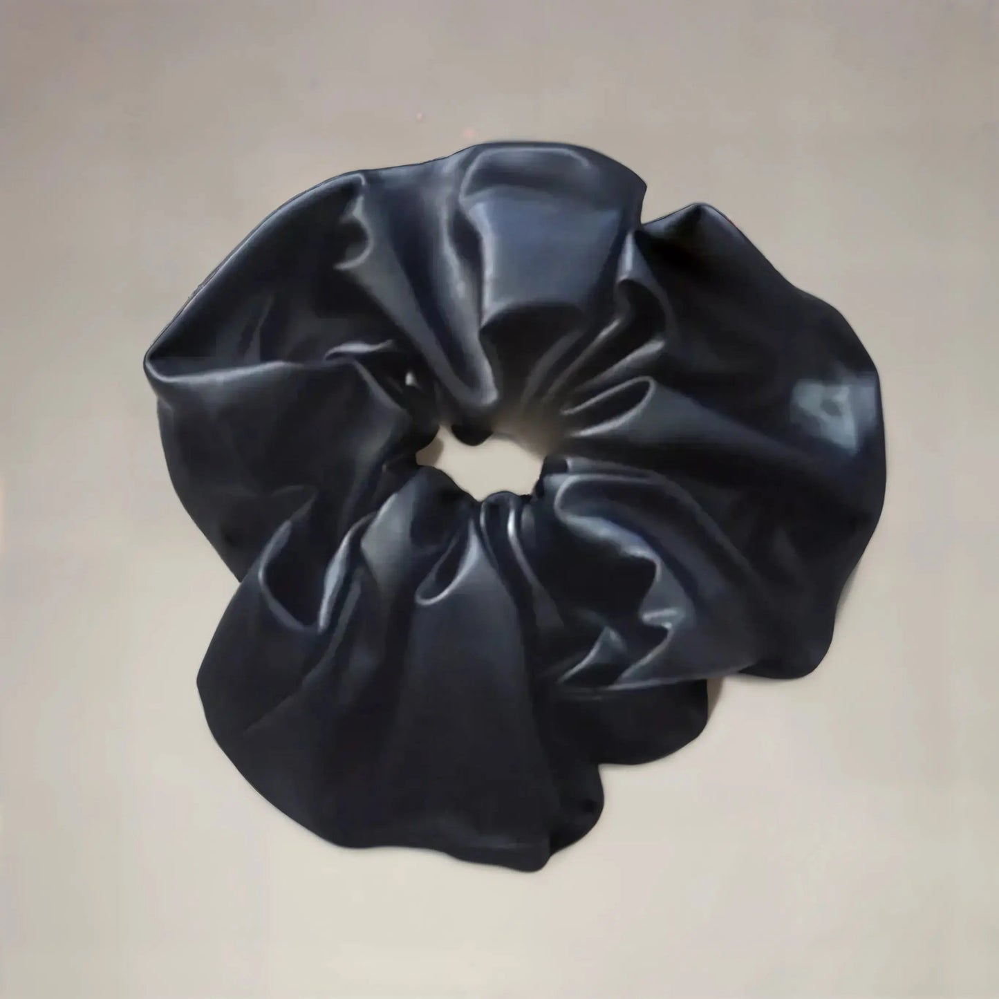 Chouchou XXL noir en simili cuir, effet brillant et volume élégant pour coiffure moderne.