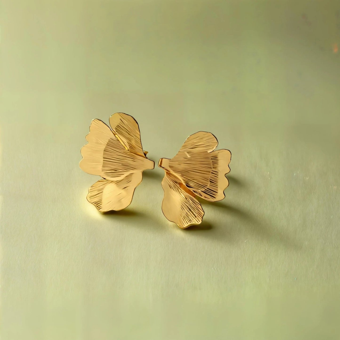 Boucles d’oreilles dorées en inox, forme demi-feuille nervurée, design chic et moderne.