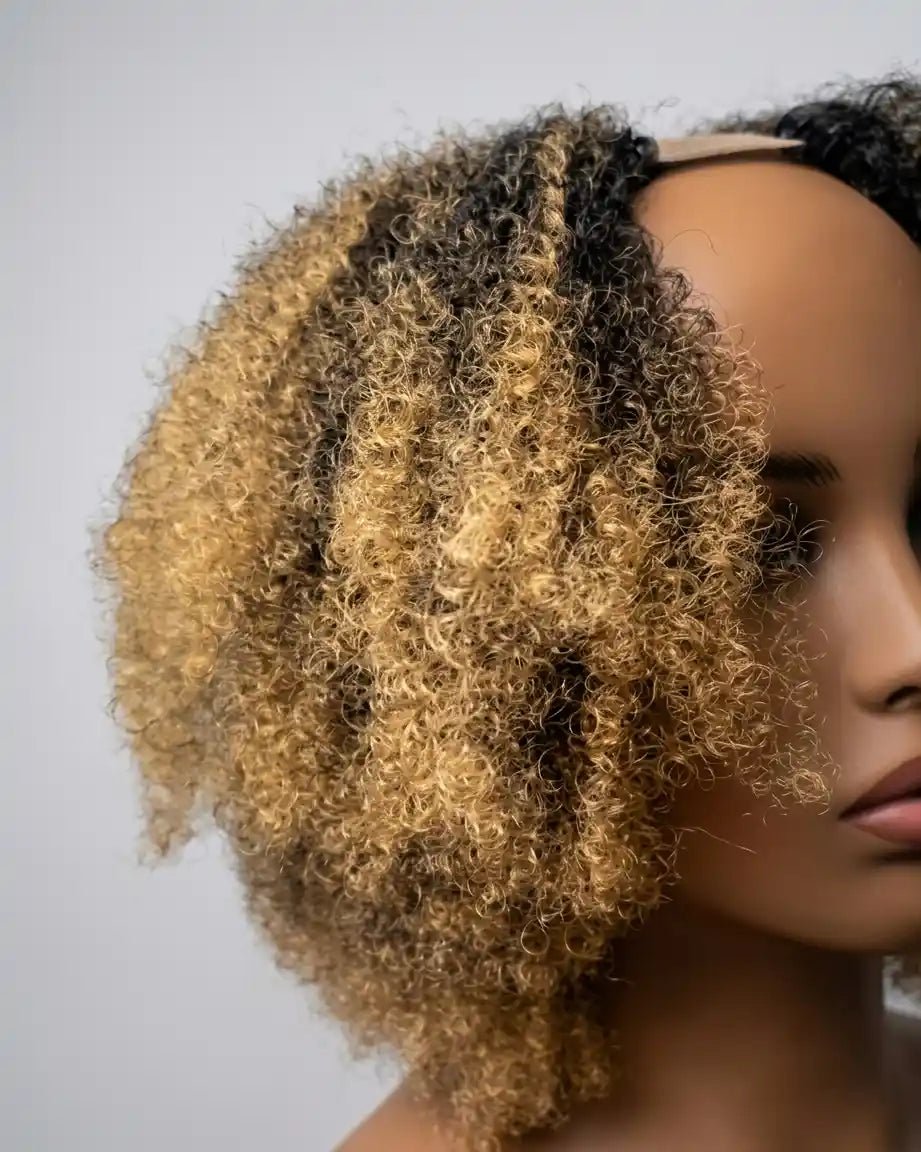 Perruque Serah en cheveux crépus synthétiques, couleur ombré noir et blond doré, avec des boucles définies et naturelles. Coiffure facile et élégante pour un look affirmé.